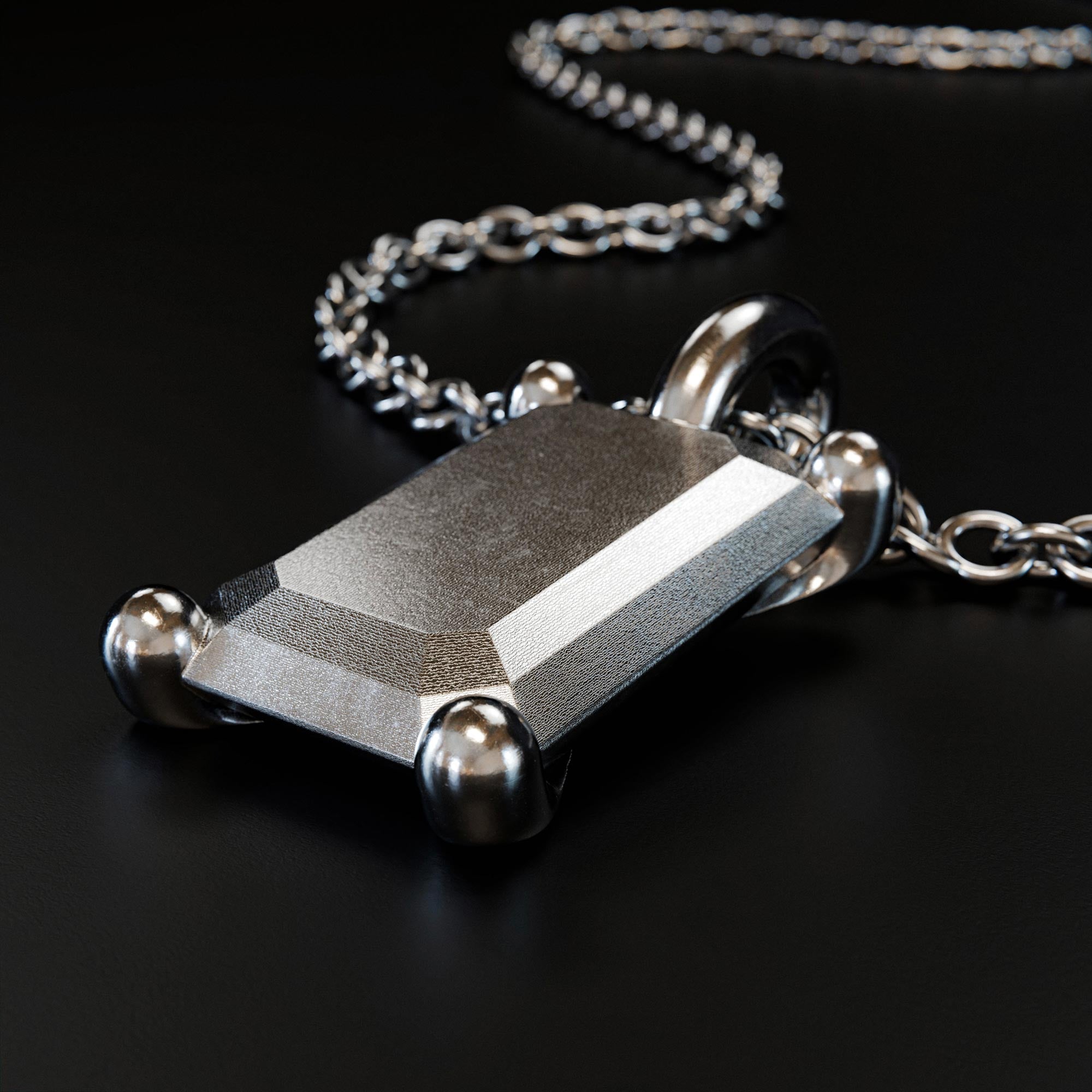 Detail view of the handmade large platinum emerald charm from the LOST collection by OFFFHAND. Designed by Michael Rüscher.